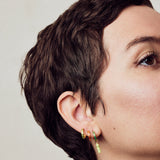 image of spark hoop enamel earrings stacked on ear with rocket enamel earrings on model with short brown hair