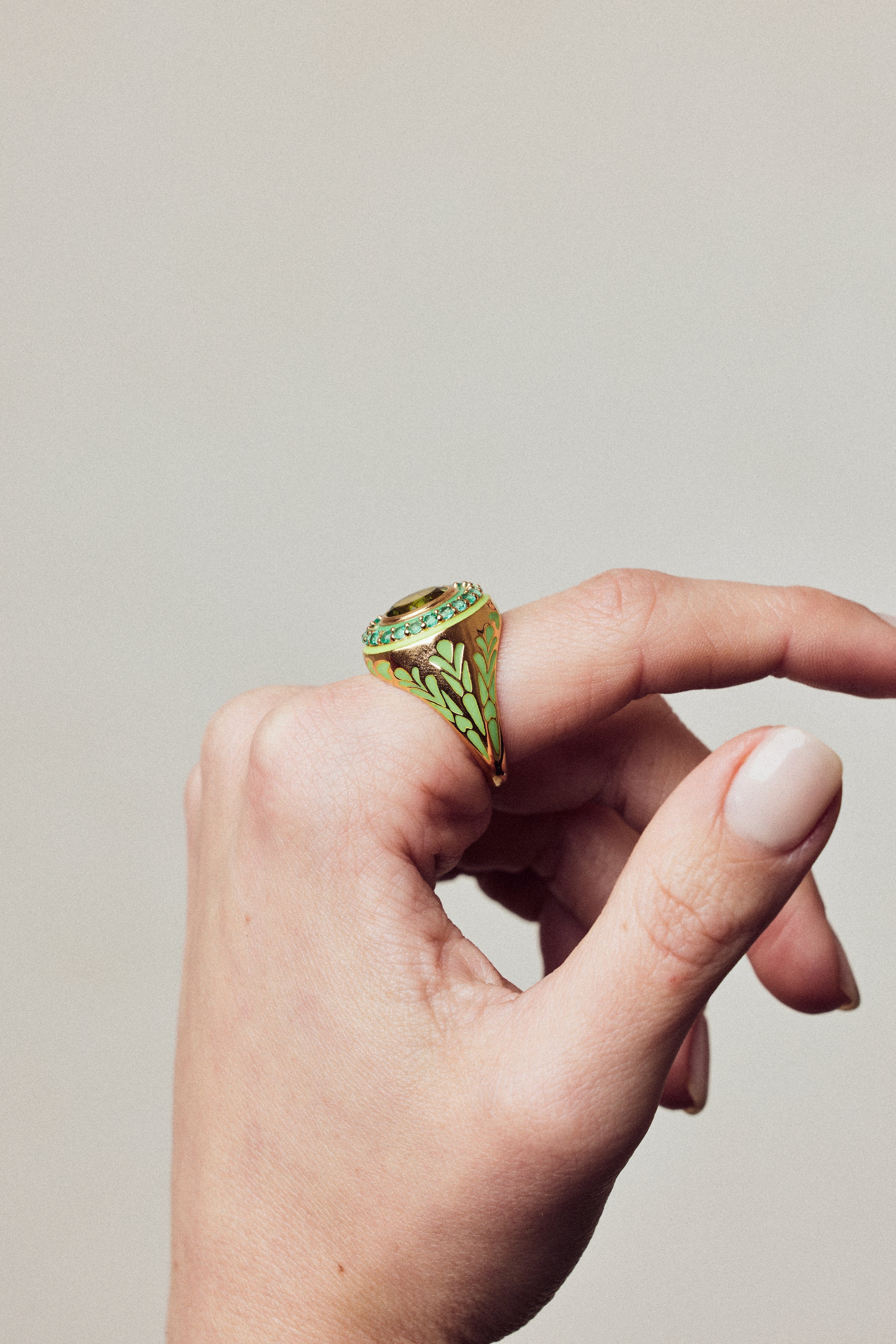 image of firework statement ring in green and gold on hand with curved fingers