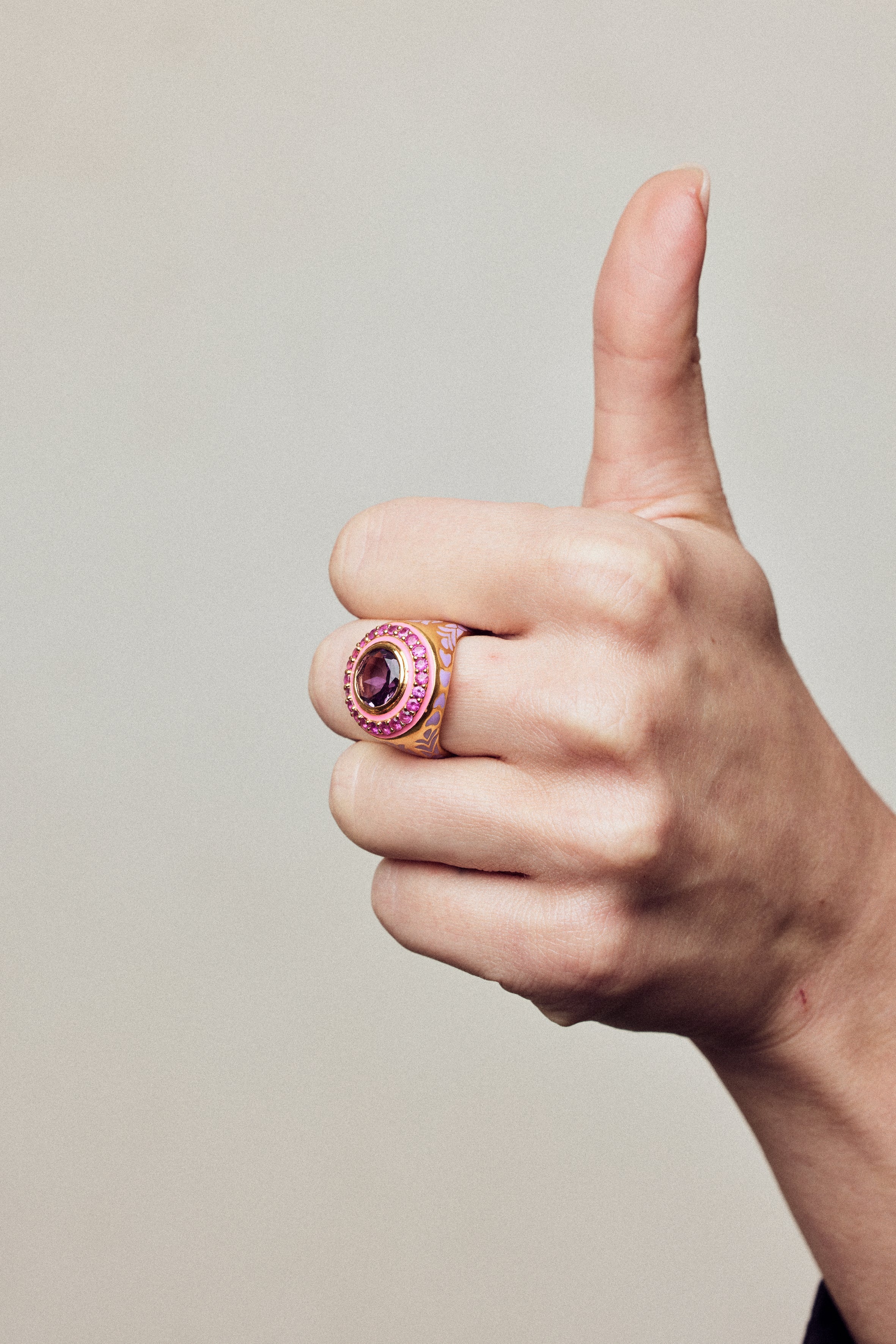 Image of statement firework ring in pink, purple and gold. On hand making thumbs up.