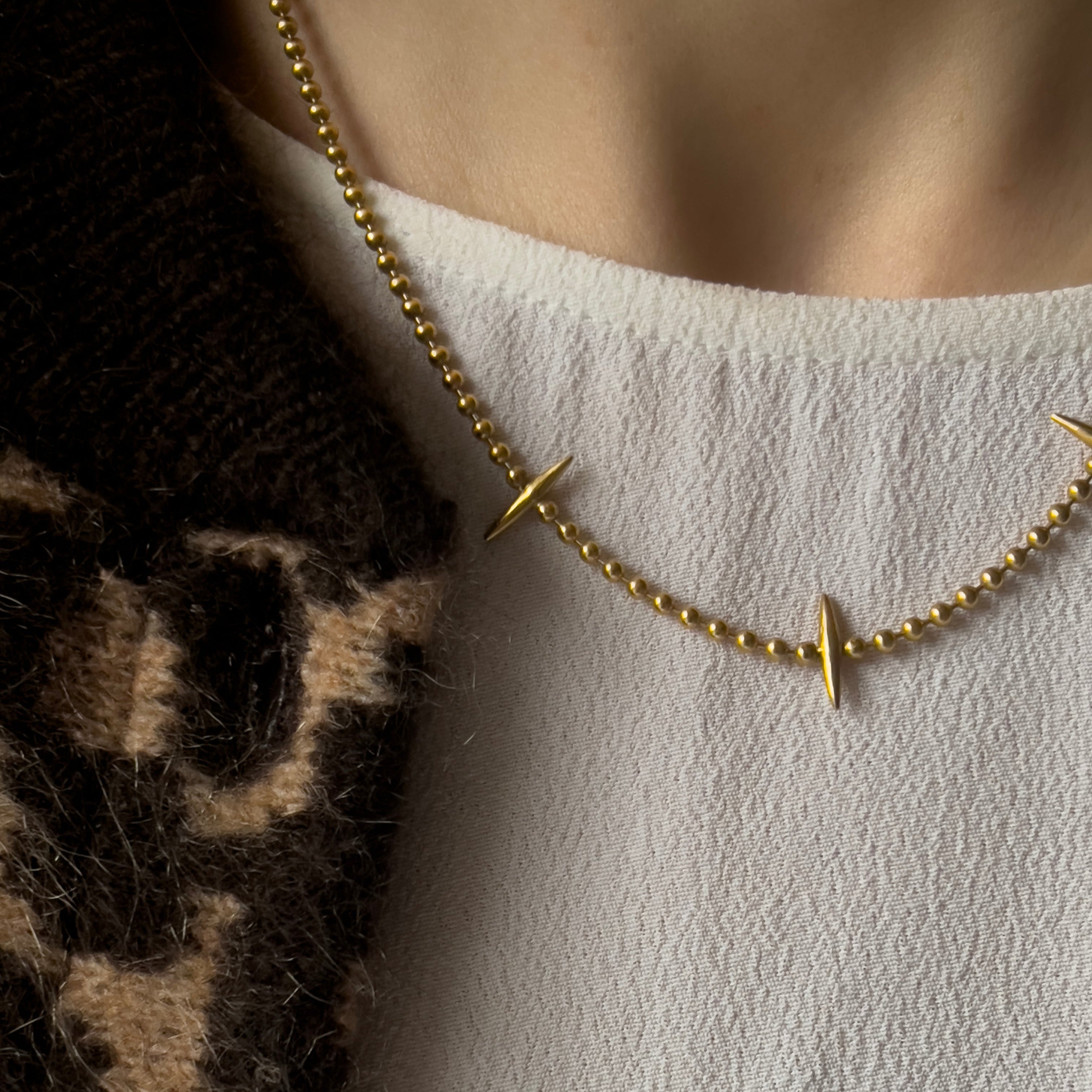 Gold vermeil necklace with 3 spikes on a ball chain. Worn with a white top and animal print bomber jacket